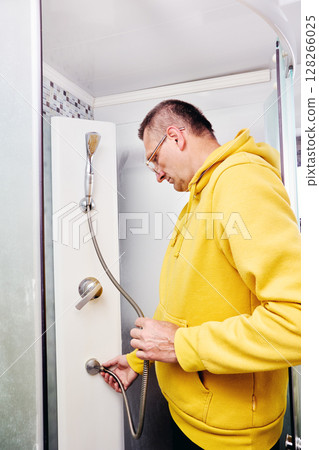 Homeowner repairs flexible shower head-in walk in shower. Homeowner repairs flexible shower head-in walk in shower. 128266025
