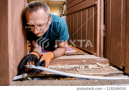 Plumber installs compression fitting to reconnect two sections of burst multilayer pipe damaged by frozen water during cold winter conditions. 128266030