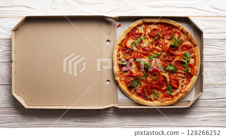 Pepperoni pizza with bell peppers and arugula in open carton box on white wooden kitchen table flat lay view. Copy-space Pepperoni pizza with bell peppers and arugula in open carton box on white wooden kitchen table flat lay view. Copy-space 128266252