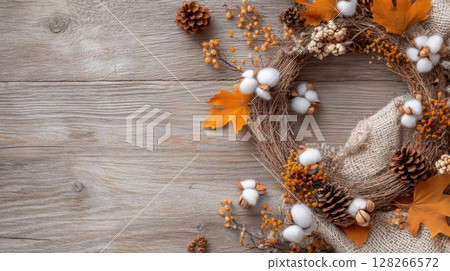 Charming still life of an autumn wreath with orange leaves, pinecones, and cotton flowers on a wooden surface Charming still life of an autumn wreath with orange leaves, pinecones, and cotton flowers on a wooden surface 128266572