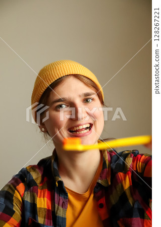 A funny and happy woman with a vibrant yellow toothbrush showing off her healthy teeth in a wide smile, perfect for a dental ad with a hipster vibe A funny and happy woman with a vibrant yellow toothbrush showing off her healthy teeth in a wide smile, perfect for a dental ad with a hipster vibe 128267221