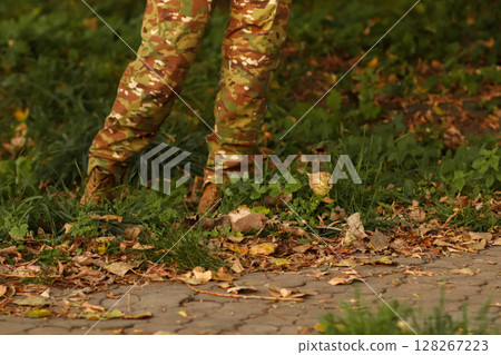 A Ukrainian military woman or man in camouflage uniform, marching through an autumn landscape, representing national intelligence and disciplined service A Ukrainian military woman or man in camouflage uniform, marching through an autumn landscape, representing national intelligence and disciplined service 128267223