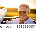 Mature man enjoying convertible ride at sunset 128269065