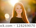 Portrait of redhead woman smiling with backlight at sunset 128269070