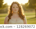 Redhead bride with curly hair wearing a white strapless wedding dress in golden sunlight 128269072