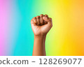 Raised fist symbolizing strength and resistance on rainbow background 128269077