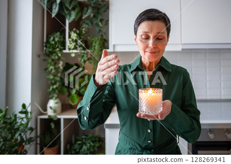 Tranquil woman inhaling candle scent, aromatherapy treatment rest. Mindfulness, self care at home 128269341