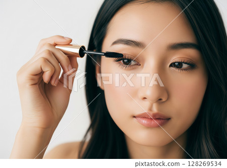 一位化著自然妝容的女模特兒正在塗睫毛膏，並仔細地整理睫毛 128269534