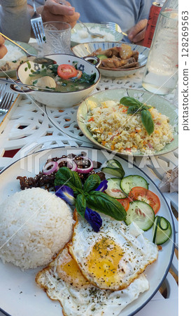 Eating classic traditional Filipino breakfast with eggs, rice, chicken adobo, tinola or moringa clear soup and beef tapa garnished with basil and onions on a decorative table. Authentic local food of Eating classic traditional Filipino breakfast with eggs, rice, chicken adobo, tinola or moringa clear soup and beef tapa garnished with basil and onions on a decorative table. Authentic local food of 128269563