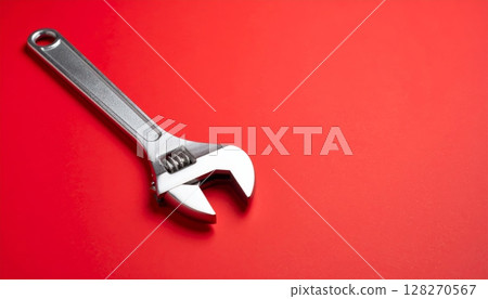 Adjustable metal wrench tool isolated on a red background for repair and construction 128270567