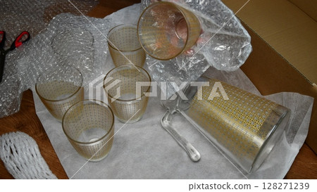 Packing up glassware into plastic bubble wrapping Packing up glassware into plastic bubble wrapping 128271239
