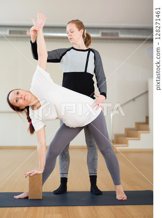 Pregnant woman practices yoga with an instructor. Extended Side Angle Pose or Parivrtta Parsvakonasana 128271461