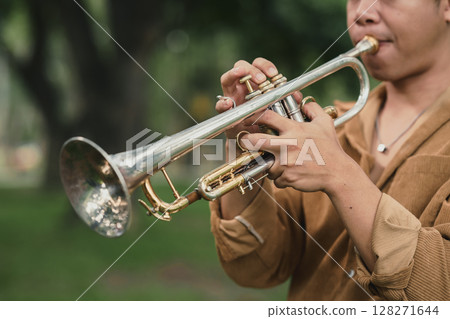 Male trumpet player performing solo in a peaceful green park Male trumpet player performing solo in a peaceful green park 128271644