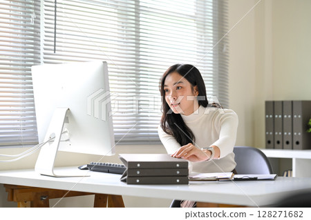 Focused woman working on a desktop computer at a bright, modern office desk 128271682