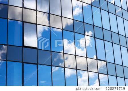The clouds can be seen beautifully reflected in the glass windows of a building 128271719