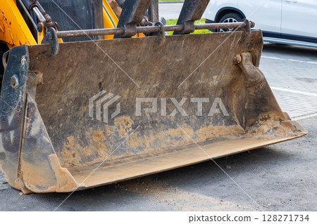 In a parking lot, theres a bulldozer that has a bucket filled with dirt In a parking lot, theres a bulldozer that has a bucket filled with dirt 128271734