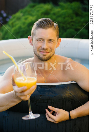 Man Relaxing In Outdoor Pool With Juice 128271772