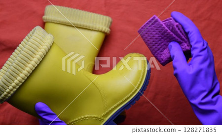 Hands in purple rubber gloves clean kids yellow rubber boots Hands in purple rubber gloves clean kids yellow rubber boots 128271835