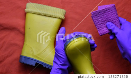 Hands in purple rubber gloves clean kids yellow rubber boots Hands in purple rubber gloves clean kids yellow rubber boots 128271836
