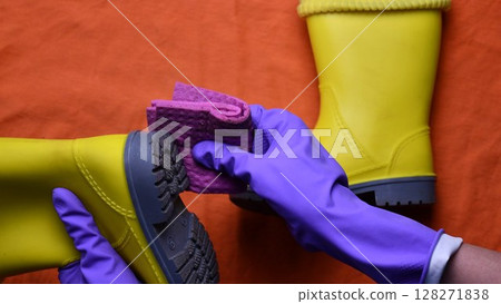 Hands in purple rubber gloves clean sole of kids yellow rubber boots 128271838