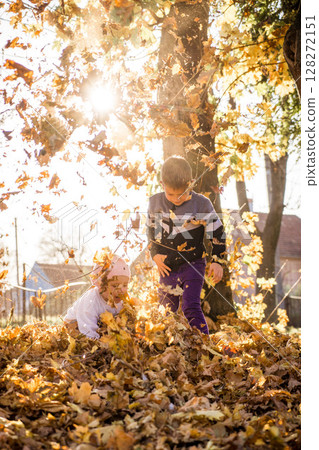 Adorable preschooler boy enjoying nice and sunny autumn day outdoors. Happy child sitting on the ground covered with autumn leaves. Outdoor fall activities for kids 128272151