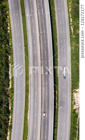 Drone shot aerial view multiple highway lanes in Thailand with few vehicles. Clean asphalt, green roadside, and minimal traffic convey efficiency and motion 128272177