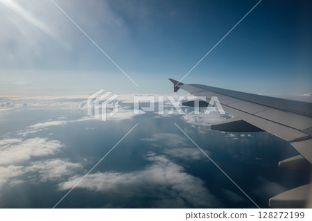 Plane wing view and blue sky with clouds Plane wing view and blue sky with clouds 128272199