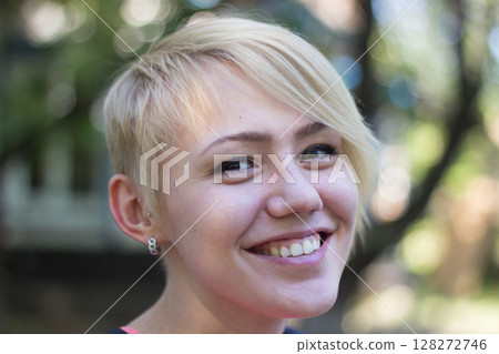 Smiling Girl With Short Hair Enjoying a Sunny Day Outdoors in a Park 128272746