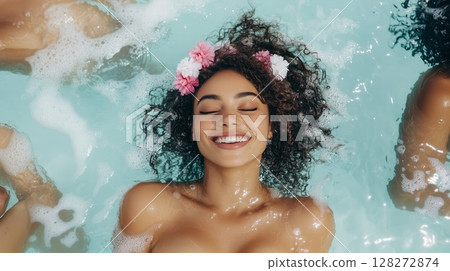 Woman Smiles Joyfully While Relaxing in a Pool Surrounded by Bubbles and Friends During a Sunny Day 128272874