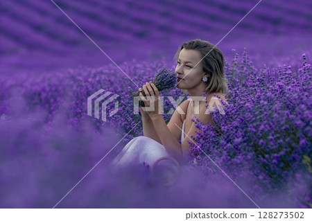 A woman is sitting in a field of purple flowers A woman is sitting in a field of purple flowers 128273502