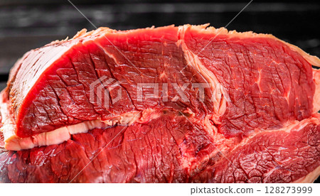 macro photo of boiled red beef meat on a black wooden surface 128273999