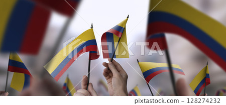 Colombia flags in their hands on a blurred urban background 128274232