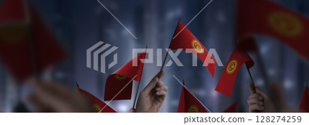 Kirghizia flags in their hands on a blurred urban background Kirghizia flags in their hands on a blurred urban background 128274259