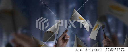 Cyprus flags in their hands on a blurred urban background 128274272