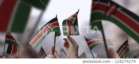 Kenya flags in their hands on a blurred urban background 128274274