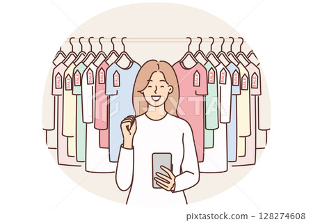 Woman with phone near hanger with T-shirts rejoices sale and opportunity to buy clothes at discounts Woman with phone near hanger with T-shirts rejoices sale and opportunity to buy clothes at discounts 128274608