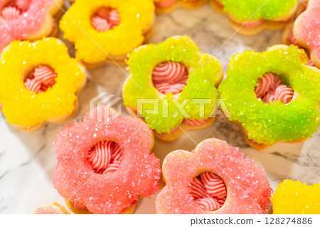 An assortment of Easter cookie sandwiches decorated with pink, green, and yellow sanding sugar, filled with raspberry buttercream. These festive cookies are part of the Easter Cookie Sandwich with 128274886