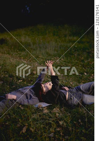 15-year-old teenage couple in love lies, sits on the grass in the park surrounded by fallen autumn leaves 128276541