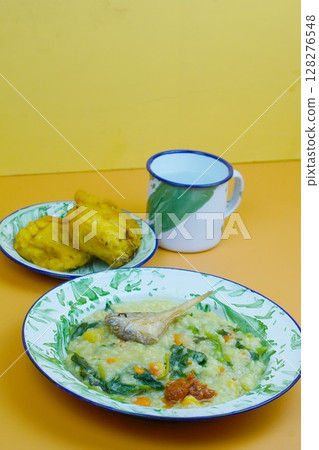 A traditional Indonesian meal featuring Bubur Manado or porridge with vegetables and salted fish on a classic plate, accompanied by fried tofu and a glass of water. A traditional Indonesian meal featuring Bubur Manado or porridge with vegetables and salted fish on a classic plate, accompanied by fried tofu and a glass of water. 128276548