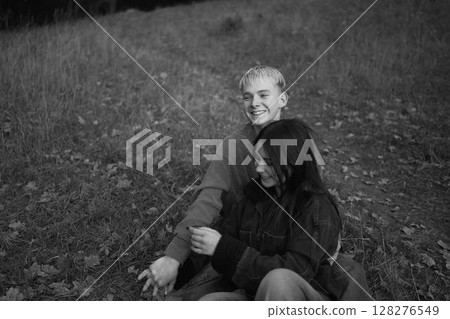 15-year-old teenage couple in love lies, sits on the grass in the park surrounded by fallen autumn leaves 15-year-old teenage couple in love lies, sits on the grass in the park surrounded by fallen autumn leaves 128276549