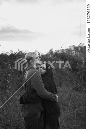 A 15-year-old teenage couple in love hugs and kisses at sunset 128276569