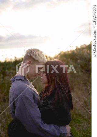 A 15-year-old teenage couple in love hugs and kisses at sunset 128276573