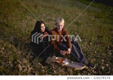 15-year-old teenage couple in love eating pizza on a picnic in an autumn park 128276578