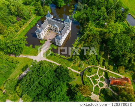 Aerial view of a historic castle surrounded by a forest, with vast green fields, winding waterways, and a river stretching across the flat Dutch countryside under a partly cloudy sky. Aerial view of a historic castle surrounded by a forest, with vast green fields, winding waterways, and a river stretching across the flat Dutch countryside under a partly cloudy sky. 128278028