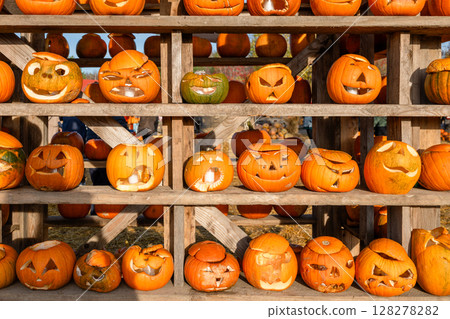 Funny carved Halloween pumpkins on wooden shelf at autumn festival 128278282