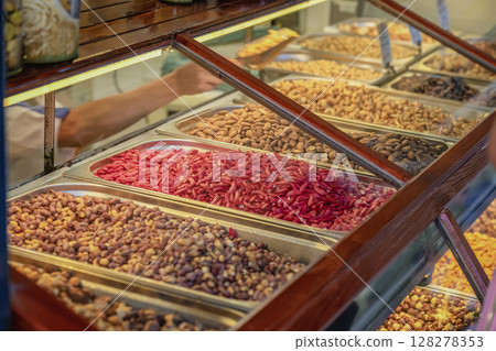 Nut, dried fruits and Spice Market. Metal trays filled with assorted nuts in traditional market stall. Concept of abundance, organic snacks, culinary diversity Nut, dried fruits and Spice Market. Metal trays filled with assorted nuts in traditional market stall. Concept of abundance, organic snacks, culinary diversity 128278353