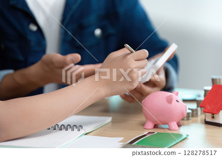 Financial Planning and Budgeting. A couple discussing savings strategies with a piggy bank and calculator. Financial Planning and Budgeting. A couple discussing savings strategies with a piggy bank and calculator. 128278517