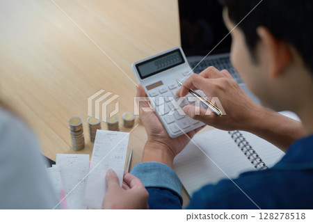 Expense Management and Budgeting. Young couple calculating finances with receipts and coins. Expense Management and Budgeting. Young couple calculating finances with receipts and coins. 128278518
