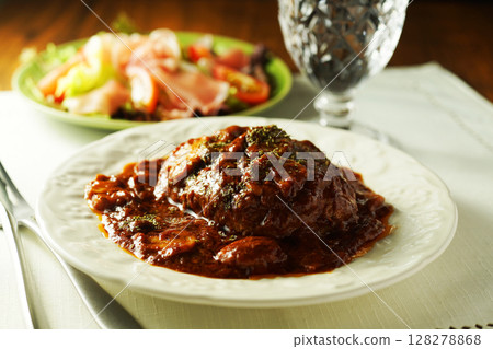 Braised hamburger steak with mushrooms and demi-glace sauce and prosciutto salad 128278868