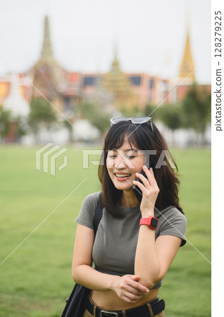 Happy southeast asian woman teenager blogger on solo tourism in Bangkok Thailand. world travel explorer using smartphone to take photo for local cultural experience concept in Asia 128279225